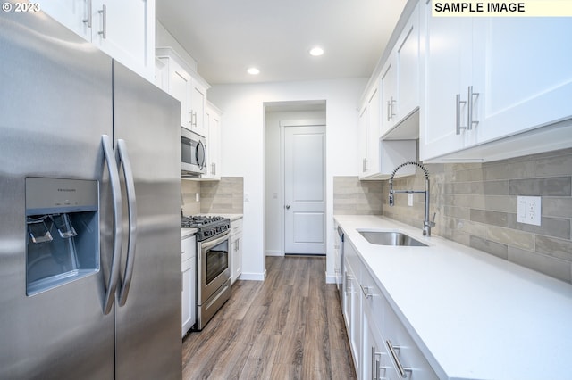 kitchen featuring a sink, white cabinetry, appliances with stainless steel finishes, light countertops, and dark wood-style flooring