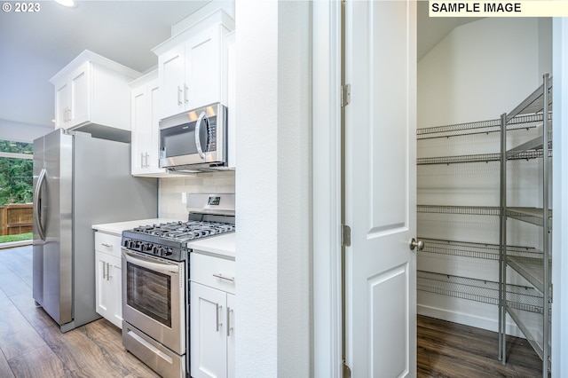 kitchen with stainless steel appliances, backsplash, dark wood finished floors, and light countertops