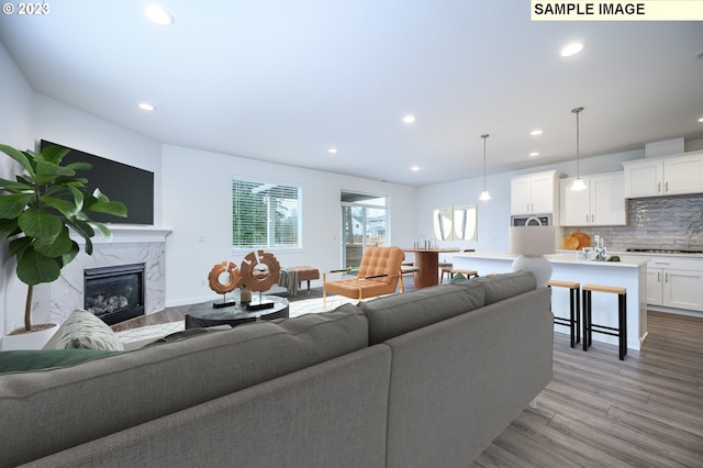 living area featuring recessed lighting, light wood-style flooring, and a fireplace