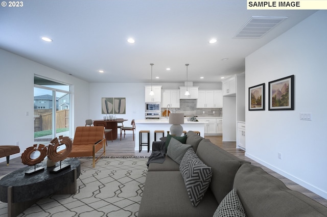 living room featuring recessed lighting, visible vents, baseboards, and light wood-style flooring