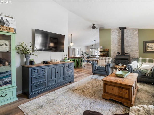 living area featuring vaulted ceiling, a wood stove, and light wood-style floors