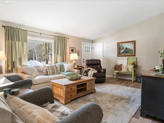 living area with light wood-type flooring, baseboards, and vaulted ceiling