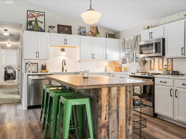 kitchen featuring a kitchen bar, a kitchen island, white cabinetry, and stainless steel appliances