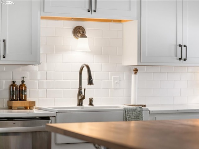 kitchen with tasteful backsplash, light countertops, dishwasher, and white cabinetry