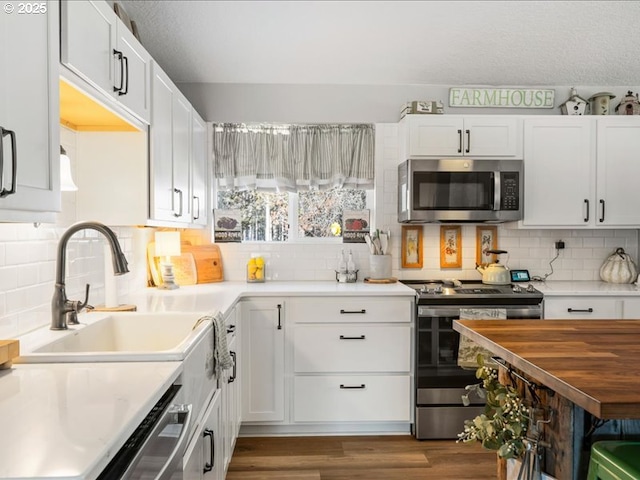 kitchen with white cabinets, a sink, stainless steel appliances, and light countertops