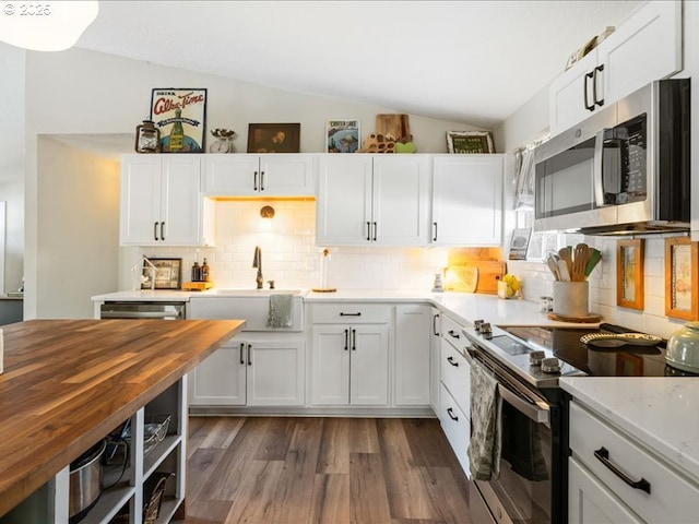 kitchen with white cabinets, lofted ceiling, wood counters, stainless steel appliances, and a sink