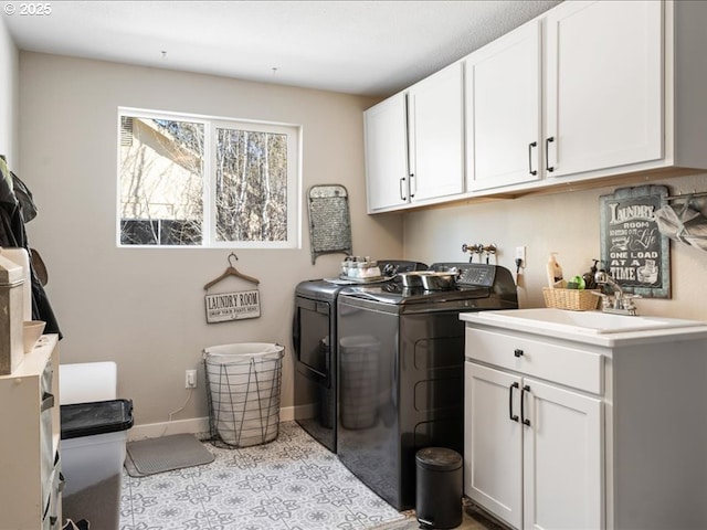 laundry room with cabinet space, washing machine and dryer, baseboards, and a sink