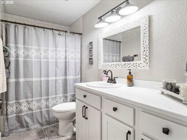 full bath featuring toilet, a textured wall, and vanity