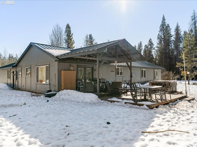 snow covered property featuring a standing seam roof, metal roof, and french doors