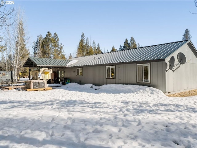 snow covered back of property with metal roof