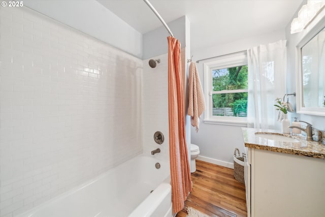bathroom with toilet, shower / tub combo, wood finished floors, vanity, and baseboards