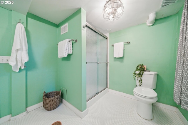 bathroom with a shower stall, toilet, and baseboards
