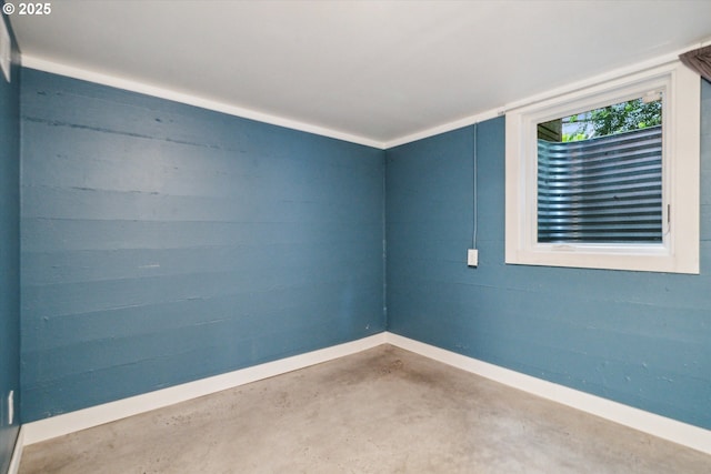 unfurnished room with baseboards and concrete floors