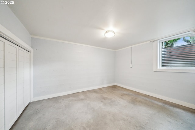 unfurnished bedroom with concrete floors, a closet, baseboards, and crown molding