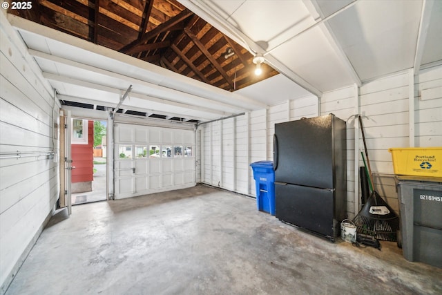 garage featuring freestanding refrigerator and wood walls
