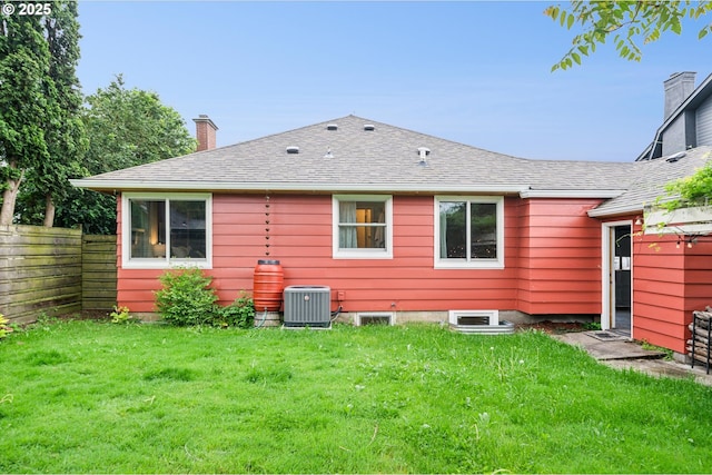 rear view of house with cooling unit, a chimney, and a shingled roof