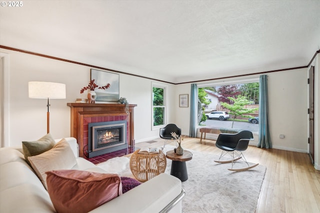 living room with hardwood / wood-style floors, a tile fireplace, baseboards, and crown molding