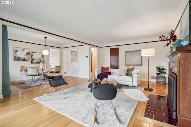 living area with baseboards, wood finished floors, and a fireplace with flush hearth