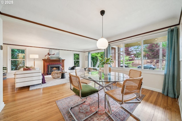 dining room with wood-type flooring, a fireplace, and baseboards