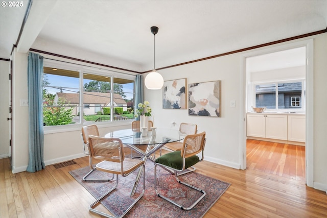dining space with light wood-type flooring and baseboards