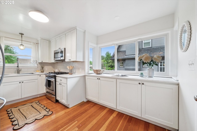 kitchen featuring appliances with stainless steel finishes, light countertops, light wood-style floors, and decorative backsplash