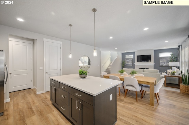 9203 S 3rd St Unit 113, Ridgefield, WA 98642 - kitchen featuring freestanding refrigerator, light countertops, light wood-style flooring, a kitchen island, and dark brown cabinetry