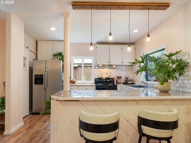 1171 Mabee Mines Rd, Washougal, WA 98671 - kitchen with stainless steel fridge, black electric range, under cabinet range hood, white cabinets, and a kitchen breakfast bar