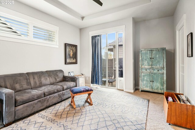 living room with carpet floors, a raised ceiling, a ceiling fan, and baseboards