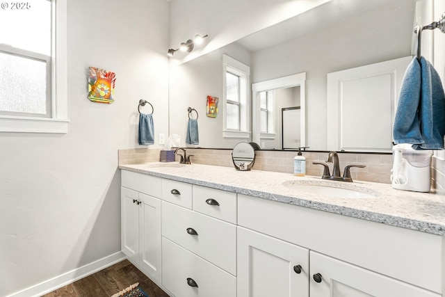 full bath with wood finished floors, tasteful backsplash, a sink, and baseboards