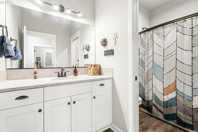 full bath featuring toilet, a shower with shower curtain, wood finished floors, vanity, and tasteful backsplash