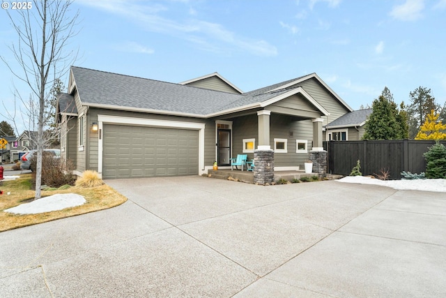 view of front of home featuring concrete driveway, roof with shingles, fence, and an attached garage