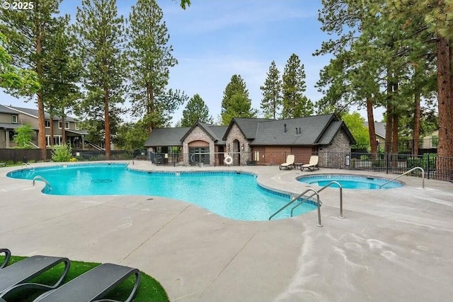 community pool with a patio, a hot tub, and fence