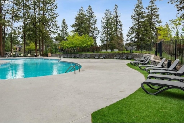 community pool with a patio area and fence