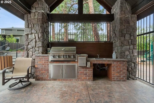 view of patio / terrace featuring a grill, fence, an outdoor kitchen, and a sink