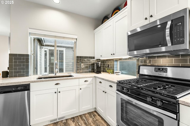 kitchen featuring wood finished floors, a sink, visible vents, white cabinets, and appliances with stainless steel finishes