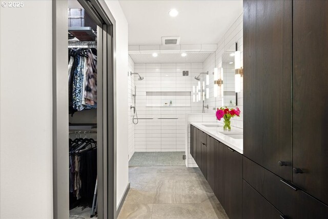 full bath featuring a shower stall, double vanity, tile walls, and a spacious closet