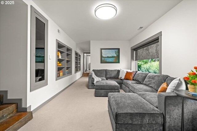 carpeted living area featuring built in shelves and stairway