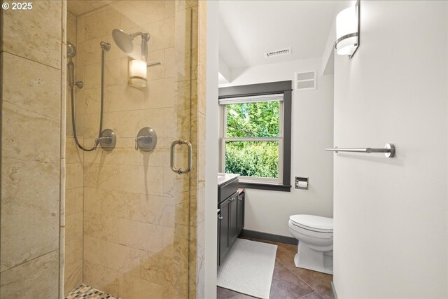 bathroom with a shower stall, tile patterned flooring, toilet, vanity, and baseboards