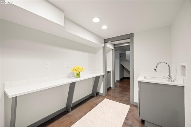 clothes washing area with a sink, recessed lighting, and baseboards