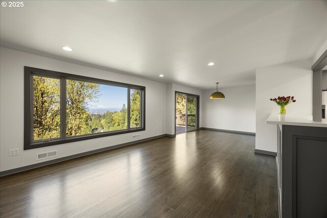 unfurnished living room with recessed lighting, dark wood-type flooring, and baseboards