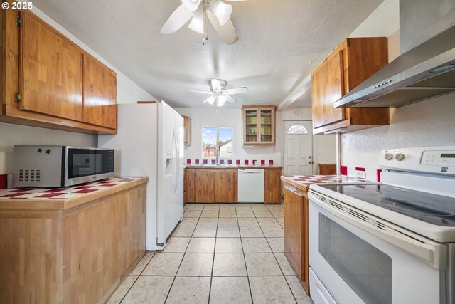 1305 E Van Buren Ave, Cottage Grove, OR 97424 - kitchen with white appliances, wall chimney exhaust hood, ceiling fan, brown cabinetry, and light countertops