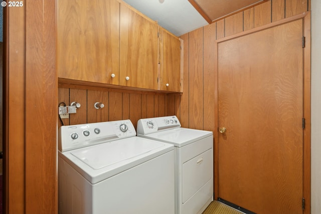 washroom featuring cabinets, washer and clothes dryer, and wood walls