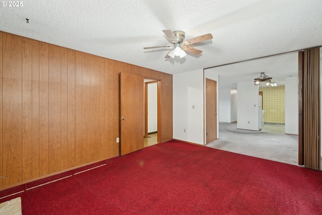 unfurnished room featuring light carpet, a textured ceiling, and wooden walls