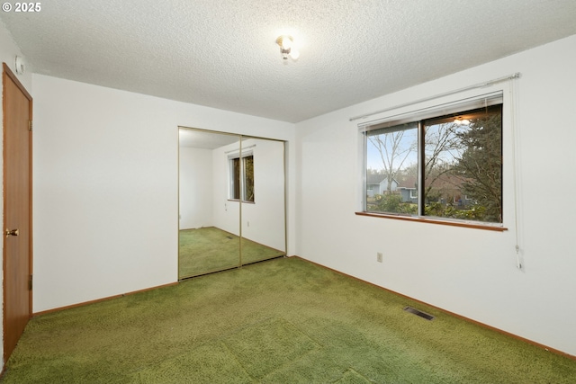 unfurnished bedroom with carpet floors, a textured ceiling, and a closet