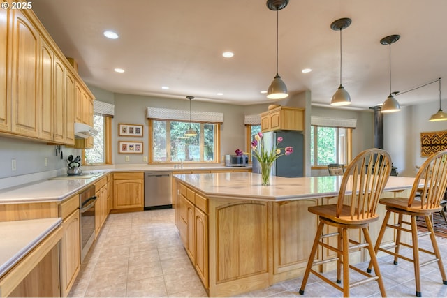 kitchen featuring appliances with stainless steel finishes, light countertops, recessed lighting, under cabinet range hood, and a kitchen island
