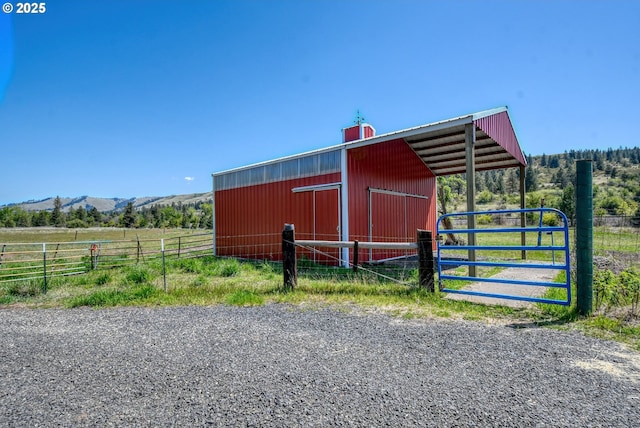 view of pole building featuring an exterior structure, a rural view, and a mountain view