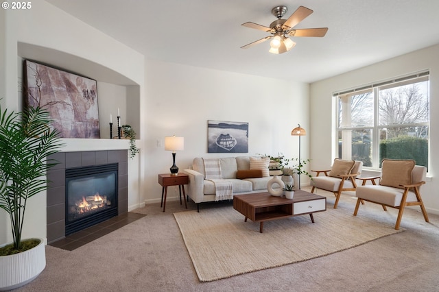 carpeted living area with a tile fireplace, a ceiling fan, and baseboards