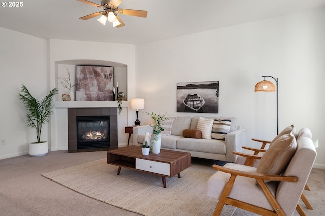 living room with a ceiling fan, carpet, baseboards, and a tile fireplace