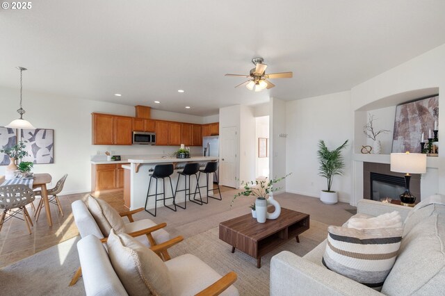 living room featuring recessed lighting, a glass covered fireplace, light carpet, ceiling fan, and baseboards