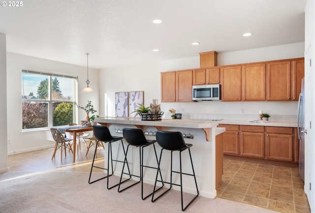 kitchen with tile countertops, appliances with stainless steel finishes, a breakfast bar, pendant lighting, and recessed lighting